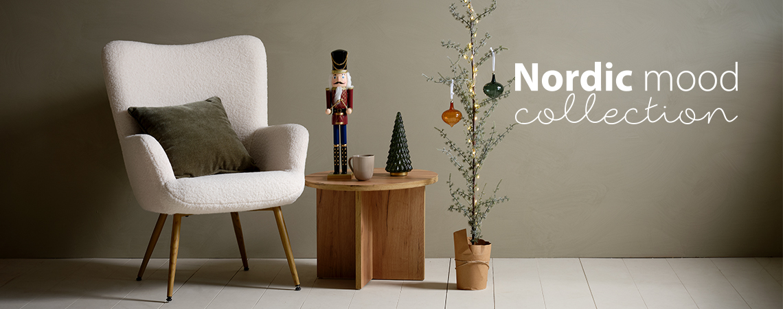 Fauteuil avec coussin, table basse avec figurine de Noël, petit arbre artificiel de Noël avec boules de verre