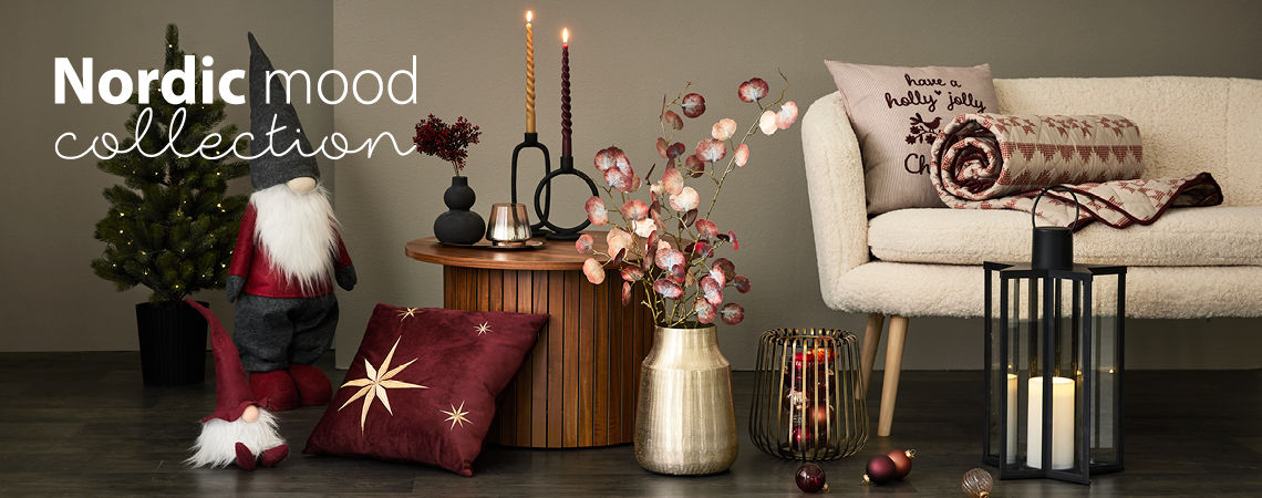 Elfes de Noël, coussins, vase doré avec des fleurs artificielles, photophore doré, lanterne noire devant un canapé blanc