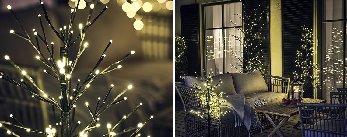 Arbres de Noël lumineux sur un patio en bois avec un ensemble lounge d’extérieur