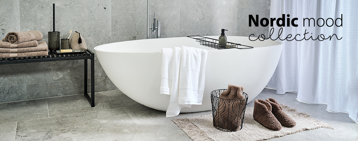 Baignoire avec support de baignoire, banc avec serviettes et set de salle de bain, chaussons sur un tapis de bain et panier avec bouillotte