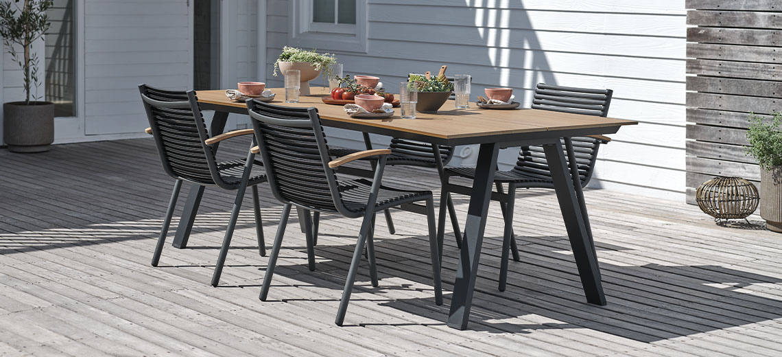 Table de jardin en bois et coloris noir et 4 chaises de jardin sur une terrasse