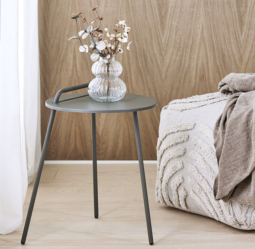 Table d'appoint minimaliste avec trois pieds et poignée, et pouf beige clair avec une surface douce à motifs