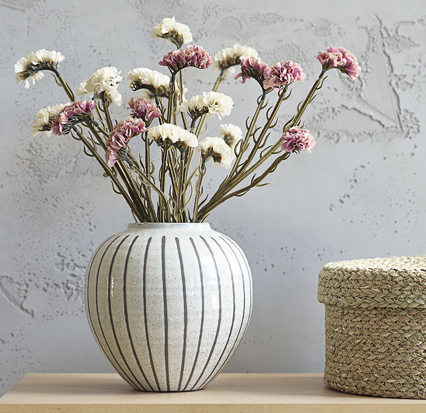 Fleurs séchées artificielles roses et blanches dans un vase blanc à rayures grises