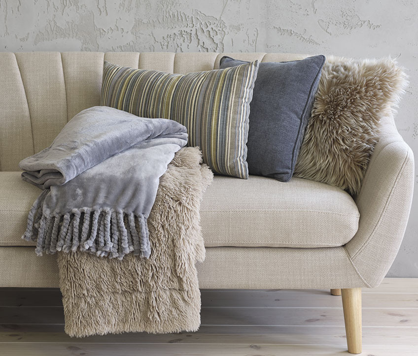 Canapé EGEDAL avec plaid polaire BONDEROSE bleu, plaid MYRFIOL en fausse fourrure, coussin rayé KORALLROT, coussin bleu HORNFIOL et coussin TAKS en fausse fourrure Canapé avec plaid polaire, coussins rayés et bleus et coussin fausse fourrure