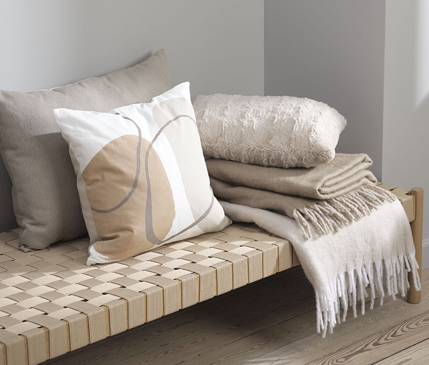 la housse de coussin POPPEL est disponible en deux combinaisons de couleurs différentes Housse de coussin à motif graphique et plaid polaire sur un banc