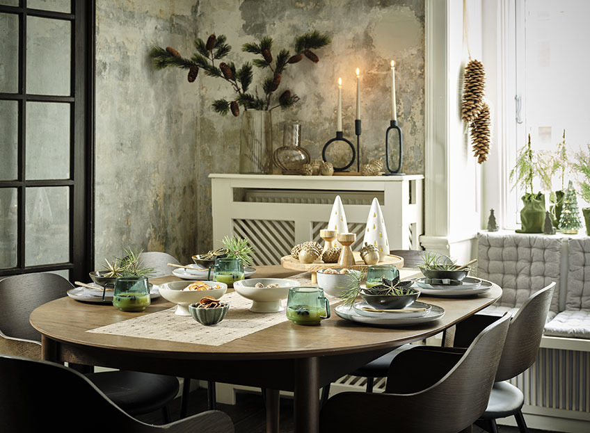 Salle à manger avec table dressée avec chemin de table de Noël, assiettes, bols et décorations de Noël
