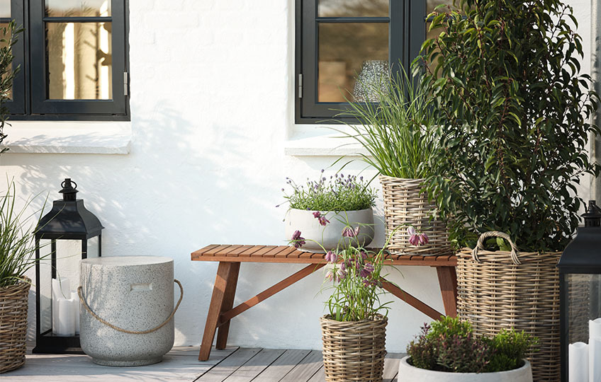 Bacs à fleurs en rotin tressé sur une terrasse