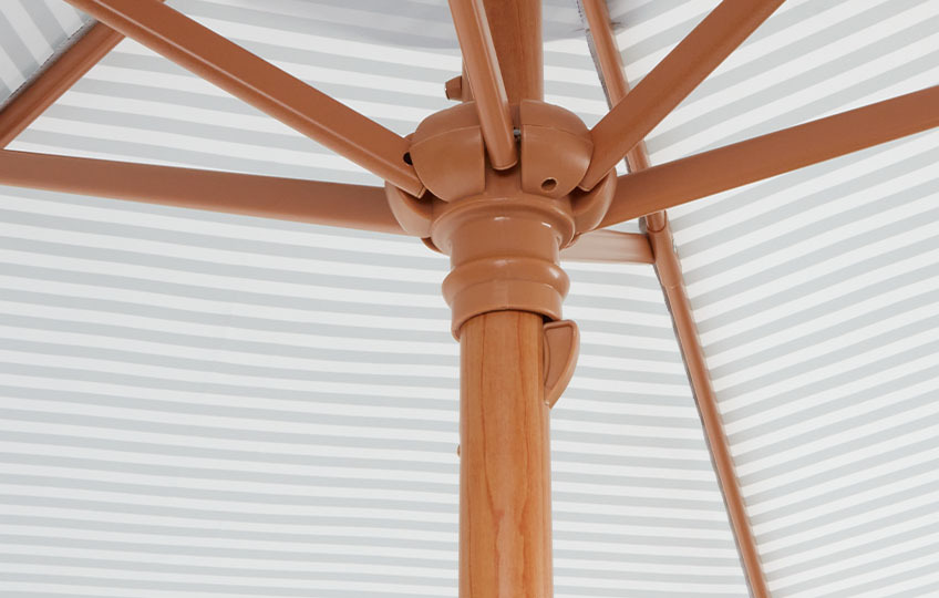 Gros plan du mât et du dessous d'un parasol de jardin recouvert d'une feuille métallique décorative