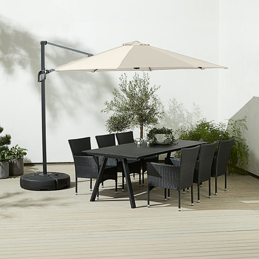 Grand parasol déporté carré de coloris blanc cassé au-dessus d’une table de jardin avec chaises de jardin