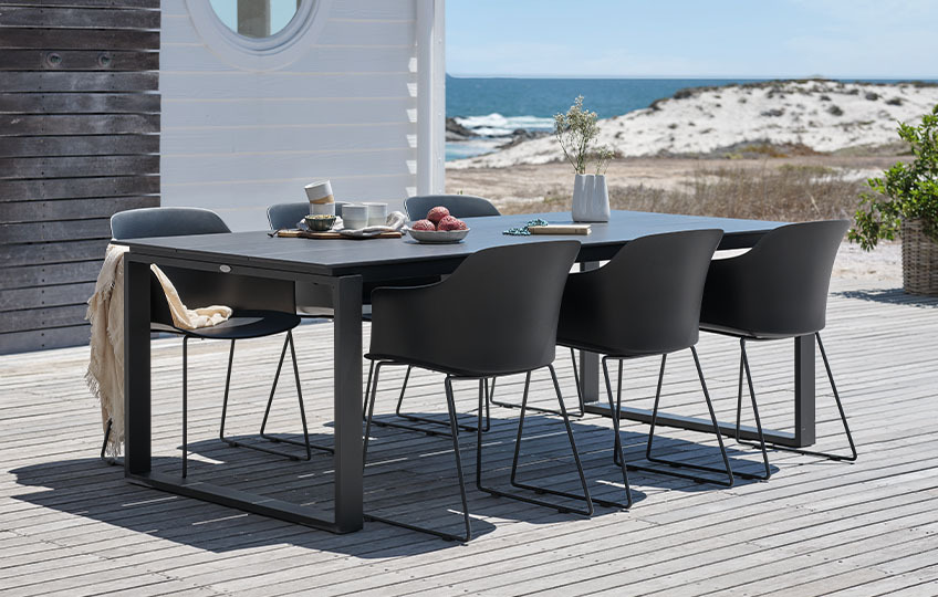 Grande table de jardin et chaises de jardin sur une terrasse à la mer