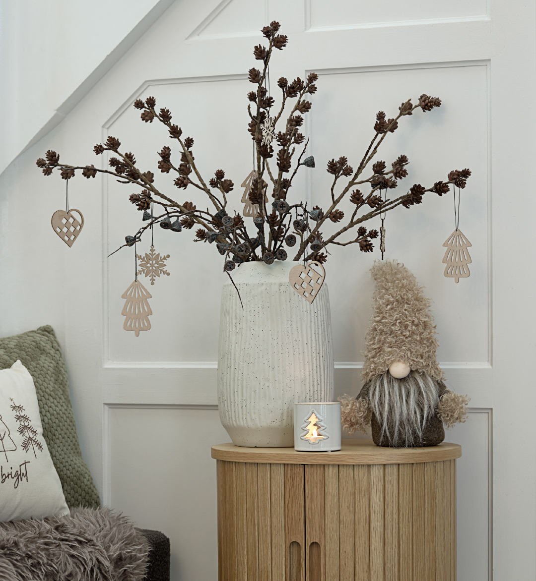 Petite table avec un vase contenant des décorations de Noël et un lutin de Noël 