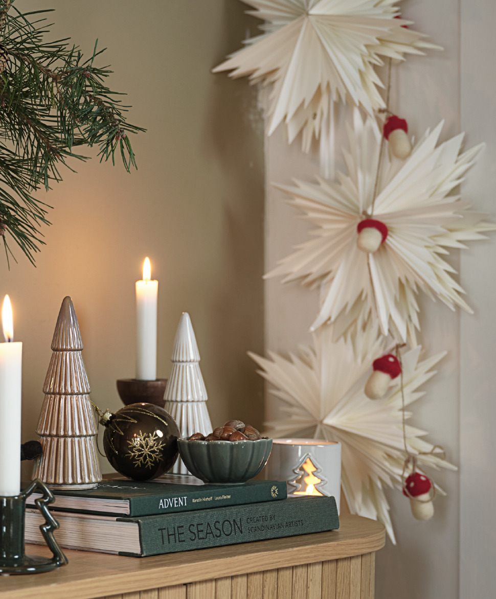 Un buffet avec d'élégantes décorations de Noël et des étoiles en papier sur le mur