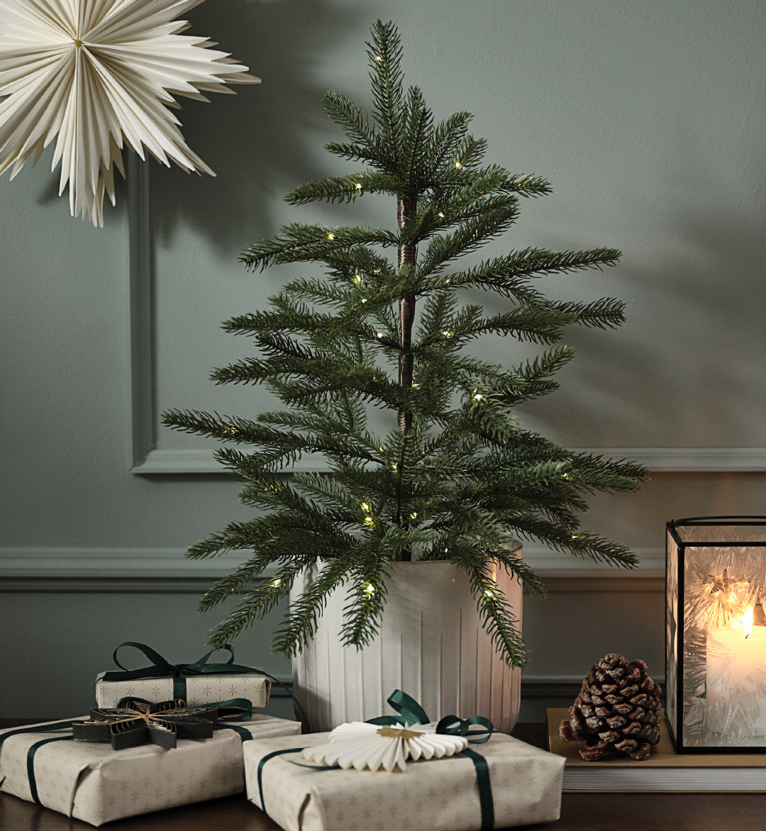 Sapin de Noël artificiel dans un pot avec des lumières et des cadeaux