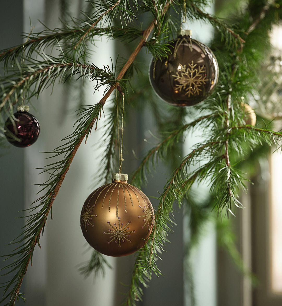 Une branche de sapin décorée avec des boules dans des tons bruns scintillants