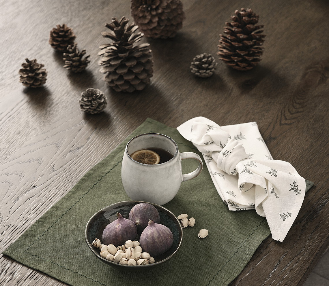 Table décorée de pommes de pin, d’un set de table avec un bol et une tasse