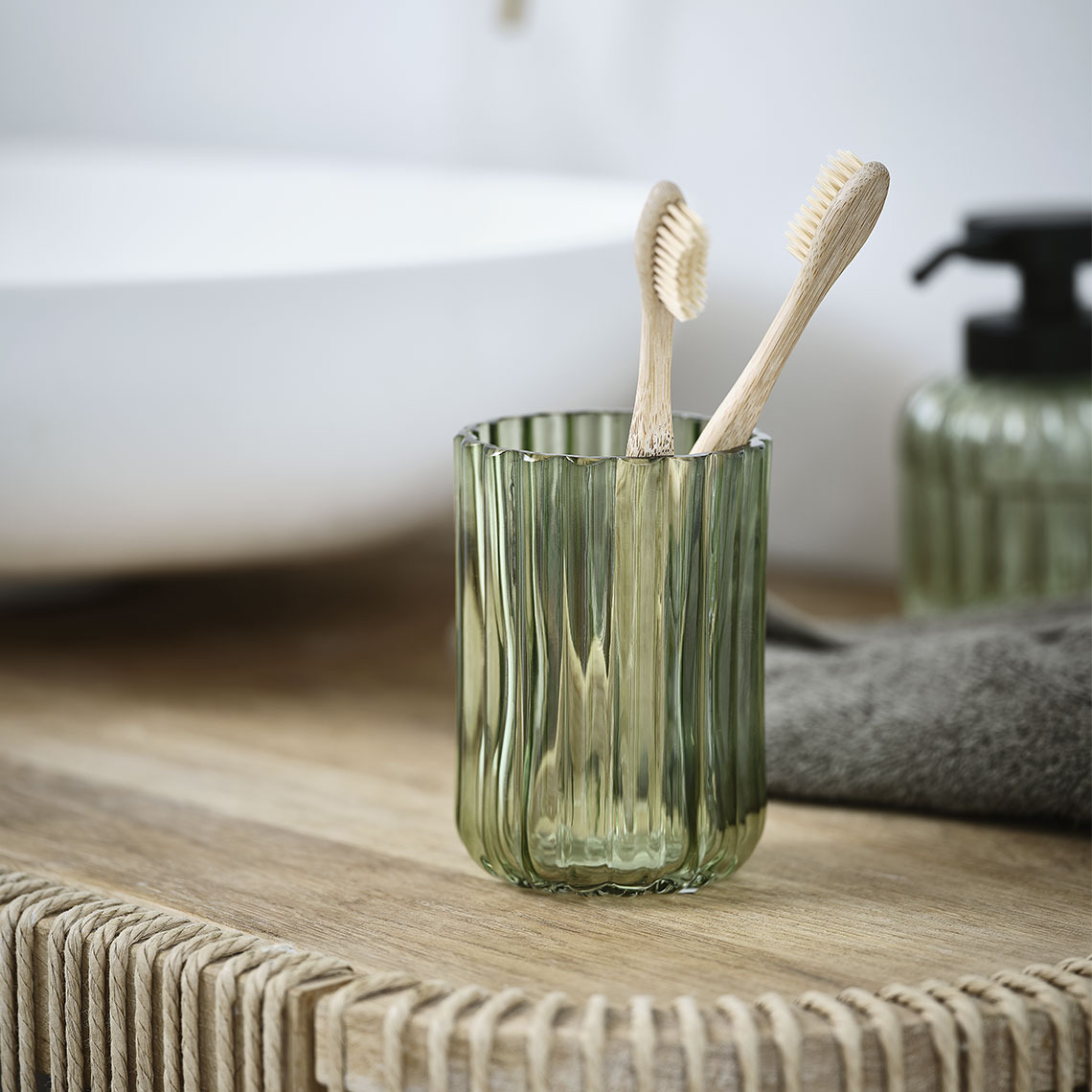 Porte-brosses à dents en verre transparent vert sur un lavabo de salle de bain