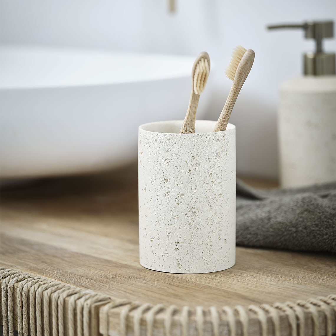 Porte-brosses à dents en grès beige sur un lavabo de salle de bain