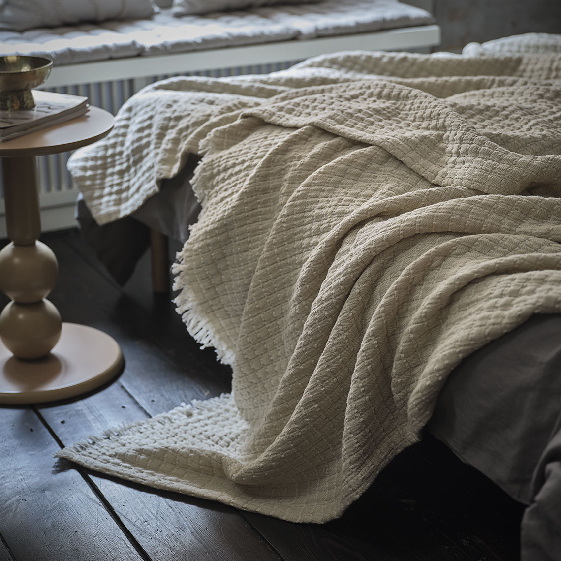 Plaid beige sur un lit dans une chambre à coucher