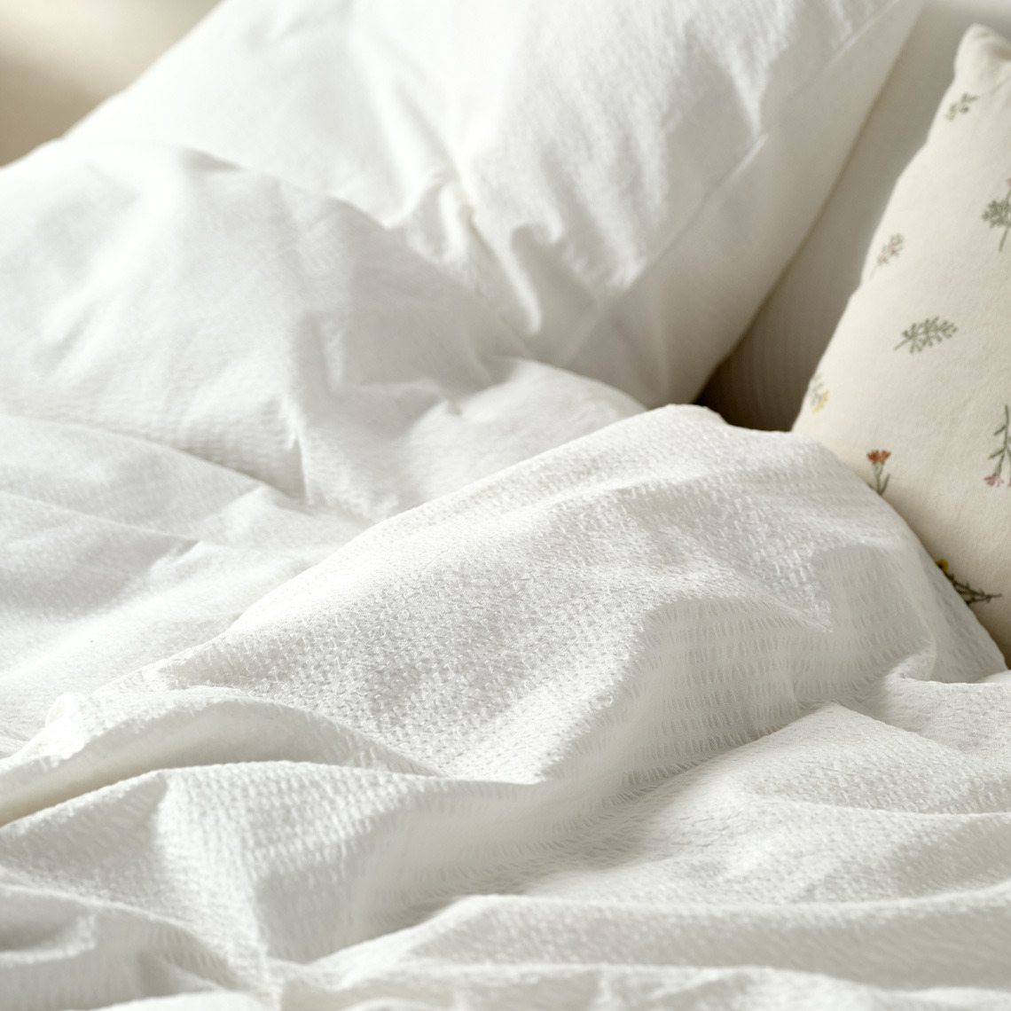 Linge de lit en tissu seersucker, idéal pour rester au frais tout au long de la nuit Linge de lit en seersucker blanc sur un lit