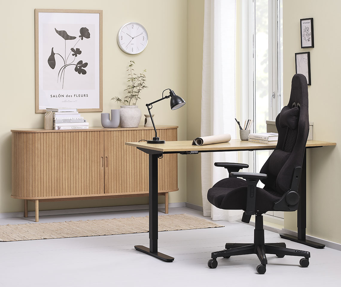 Espace de bureau à domicile avec le bureau à hauteur réglable SVANEKE, la chaise gaming NIBE et le buffet LYNGVIG Décoration de bureau chaleureuse avec un bureau à hauteur réglable, une chaise gaming et un buffet