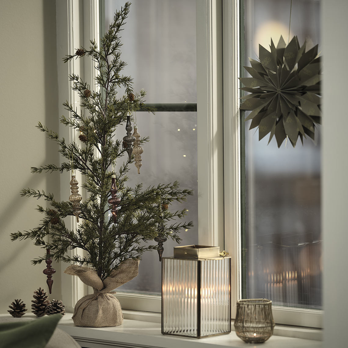 Photophore, lanterne et sapin artificiel décorant un rebord de fenêtre pour les fêtes 