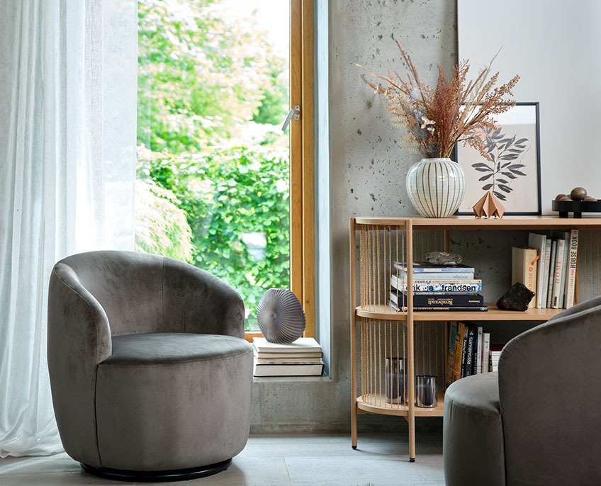 Fauteuil à accoudoirs gris, buffet avec livres et vase