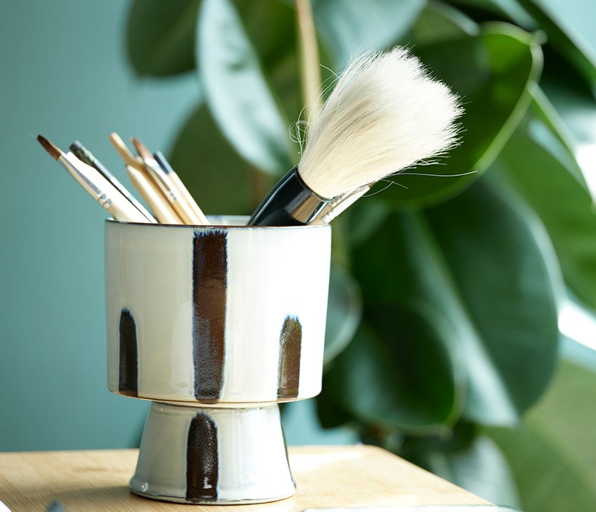 Pot de fleurs avec pinceaux sur un bureau en bambou