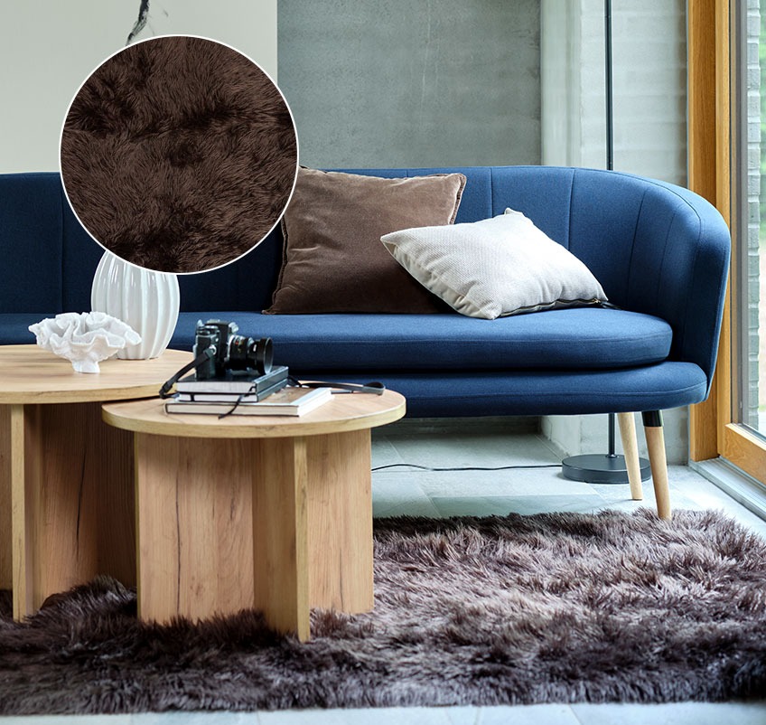 Living room with brown rug in faux fur, blue sofa and round coffee tables 