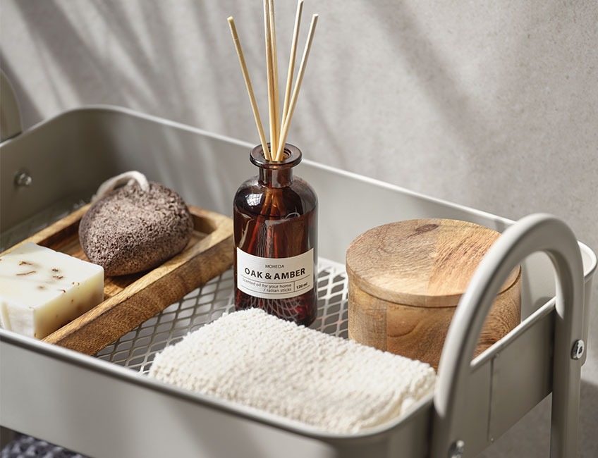 Huile parfumée MOHEDA, jarre en bois ARDALA et éponge de bain VAD sur une table console Huile parfumée, jarre en bois et éponge de bain sur une table console