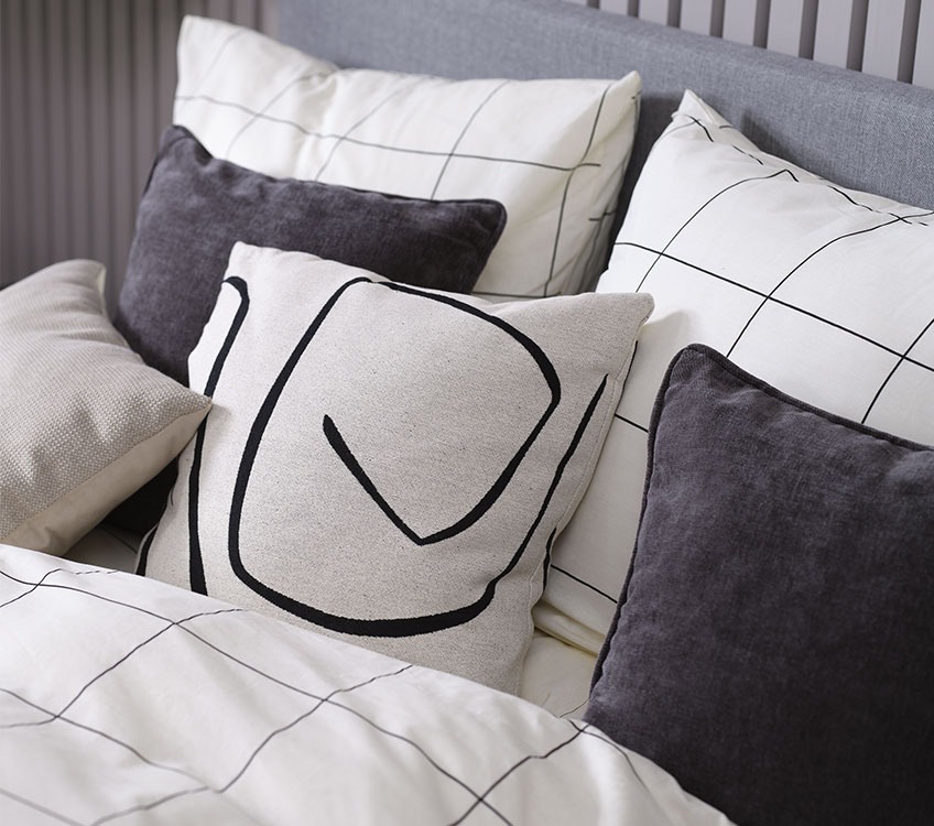 Chambre avec une parure de lit noire et blanche à carreaux et coussins décoratifs