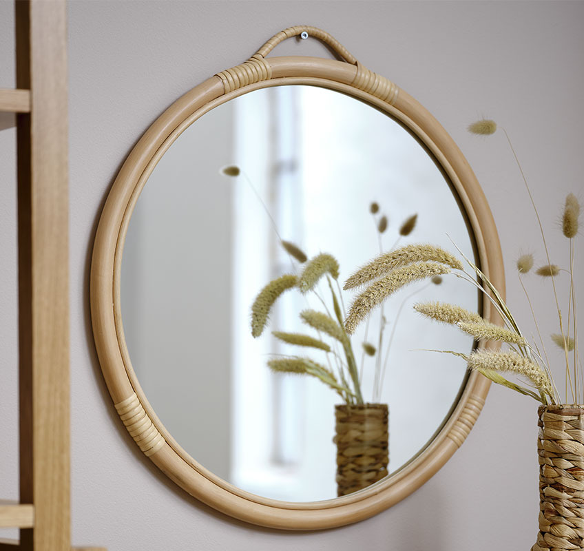 Miroir en rotin sur un mur beige 