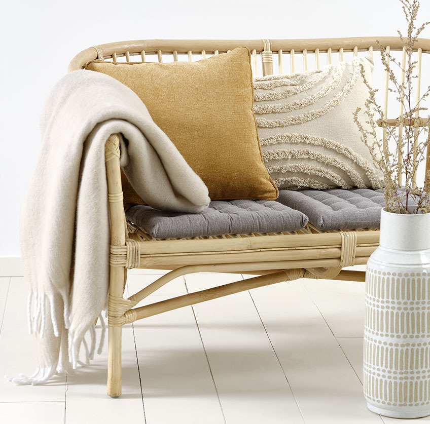 Canapé LISELEJE avec le coussin beige GRAVMYRT, le coussin jaune HORNFIOL, et le plaid TUSENFRYD Canapé en rotin avec des coussins beiges et jaunes