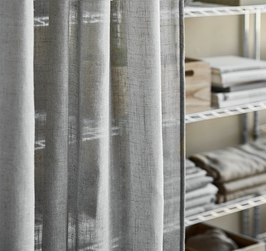 Shelving unit in metal with grey sheer curtains in front