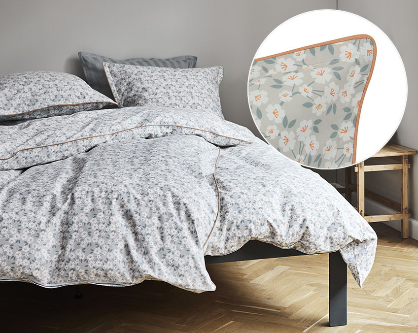 La parure de lit INGA est composée à 100% de percale de coton Parure de lit avec des fleurs sur un fond gris