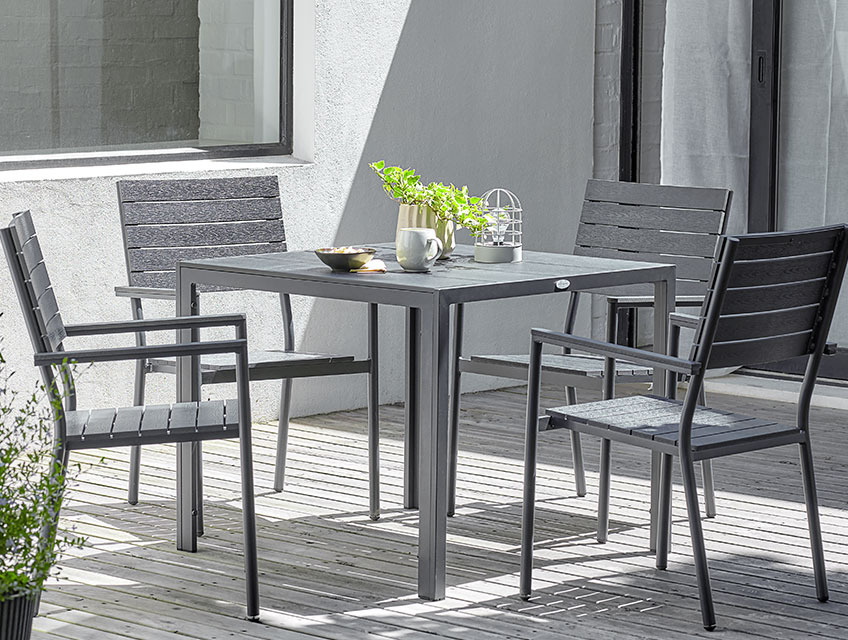 MADERUP garden table and PADHOLM garden chairs Square garden table and four stacking chairs on a sunny patio
