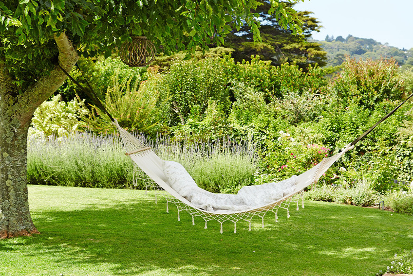 White hammock suspended between two trees in garden